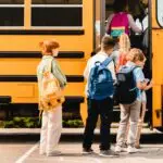 Schoolchildren kids pupils group of mixed-race classmates boarding school bus before lessons